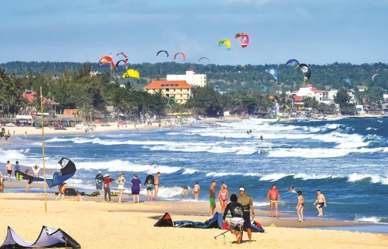 Tourists enjoying kitesurfing and beach activities in Mui Ne, Vietnam travel destination