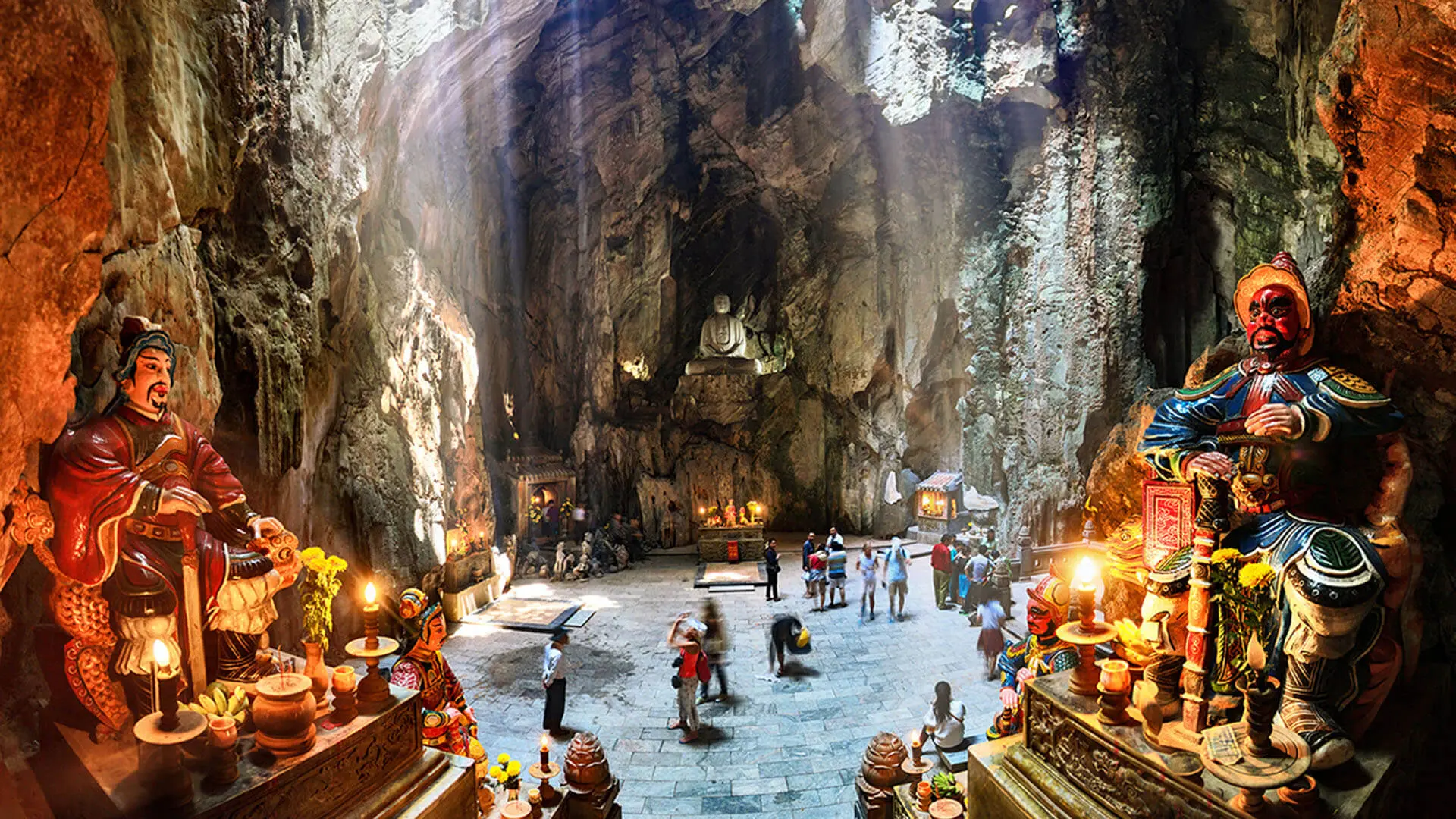 Inside a sacred cave at the Marble Mountains in Da Nang with ancient statues, natural rock formations, and visitors exploring the spiritual site