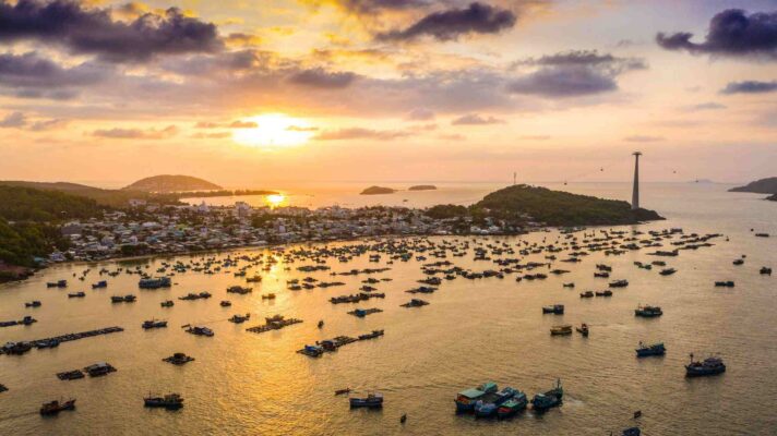 Phu Quoc beach at sunset with white sand, palm trees, and clear blue sea, a famous travel destination in Vietnam