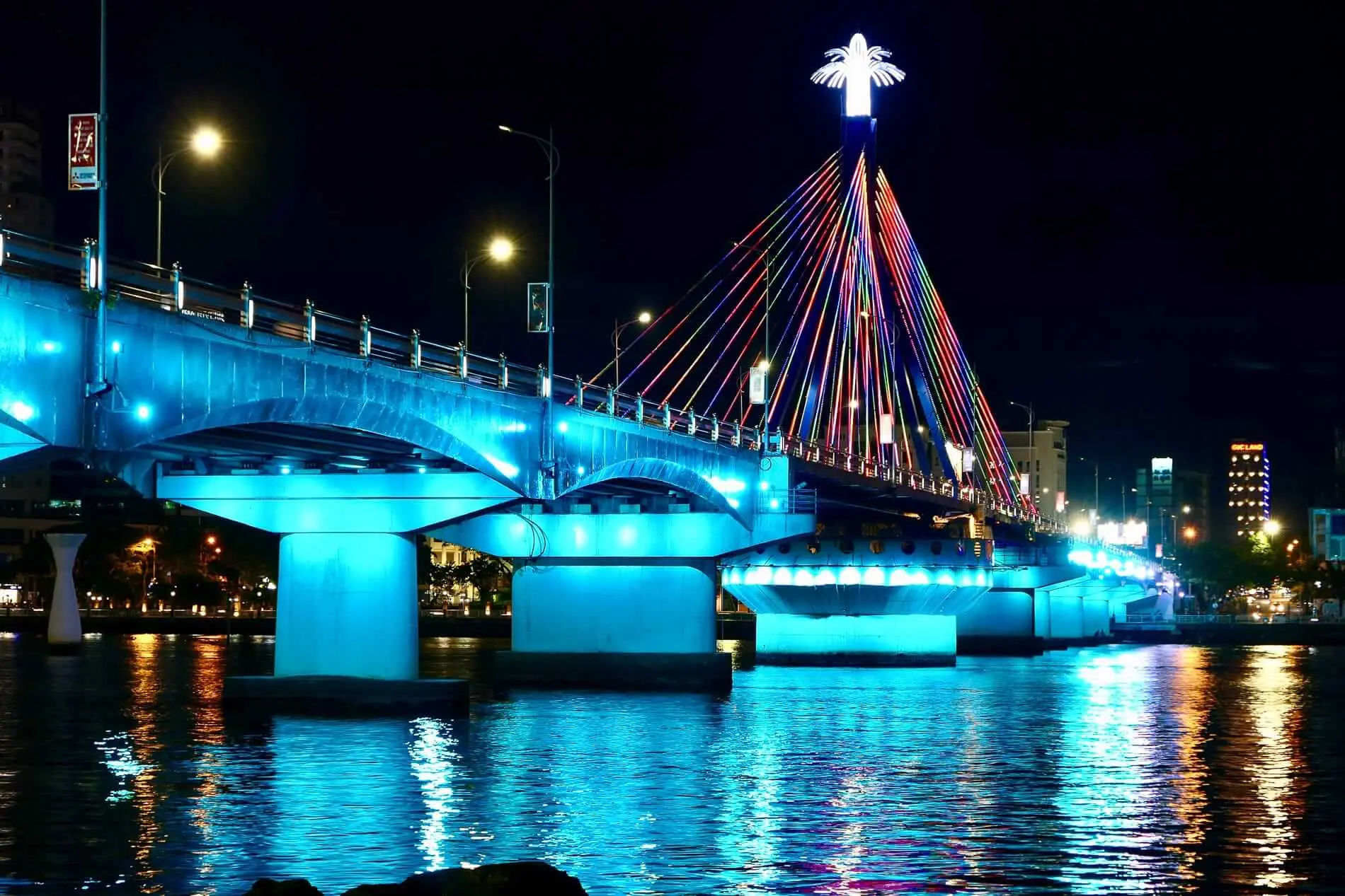 Tran Thi Ly Bridge in Da Nang illuminated at night with colorful LED cables reflecting on the Han River