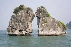 Hon Ga Choi limestone islet in Ha Long Bay rising dramatically from calm turquoise waters in Vietnam.