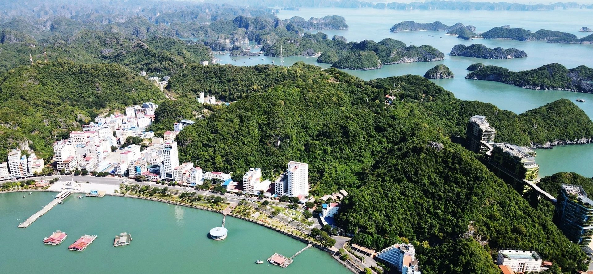 Aerial view of Cat Ba Island town surrounded by lush green mountains and Lan Ha Bay