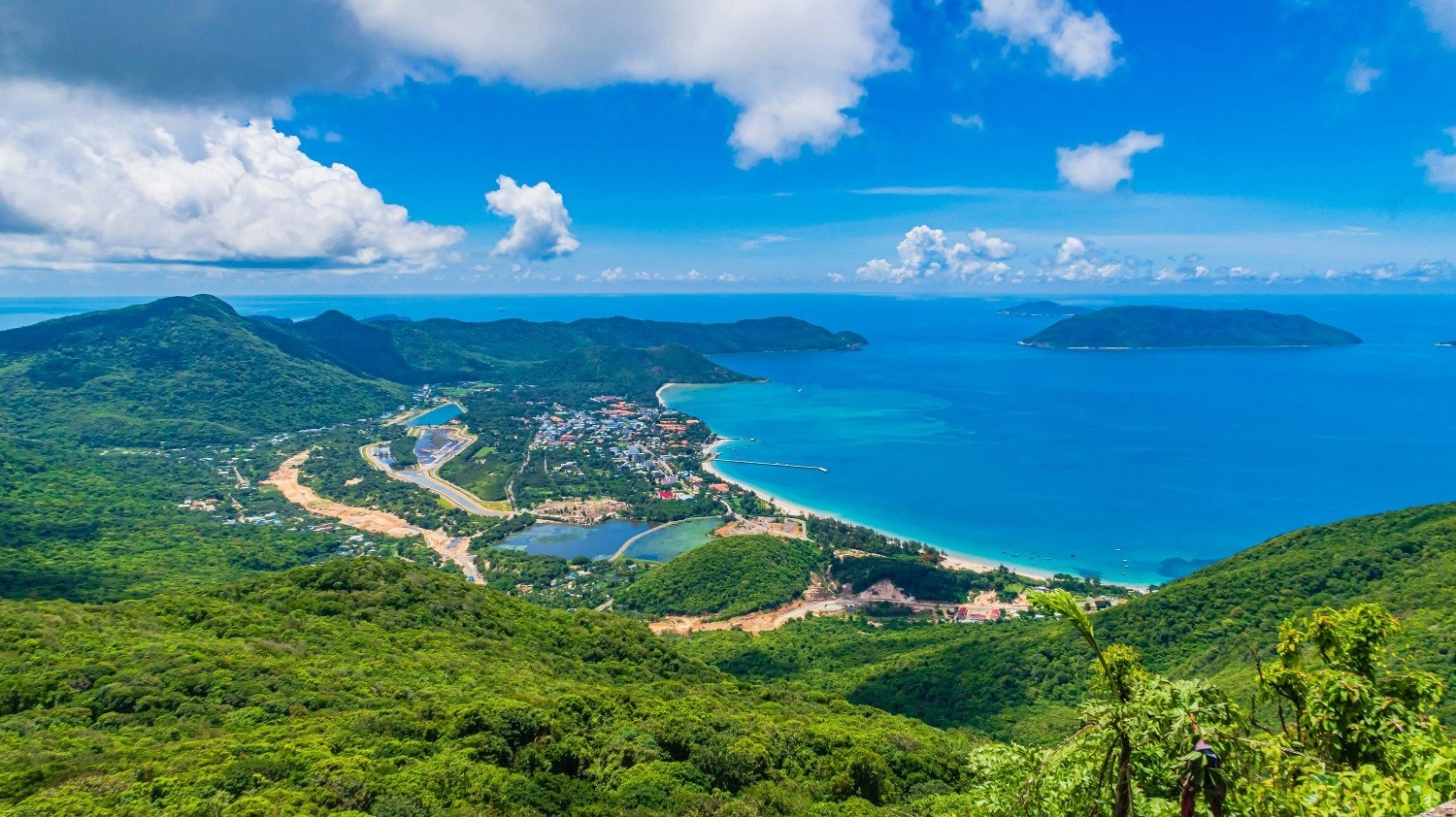 Scenic coastal road winding along turquoise sea and green mountains in Con Dao.