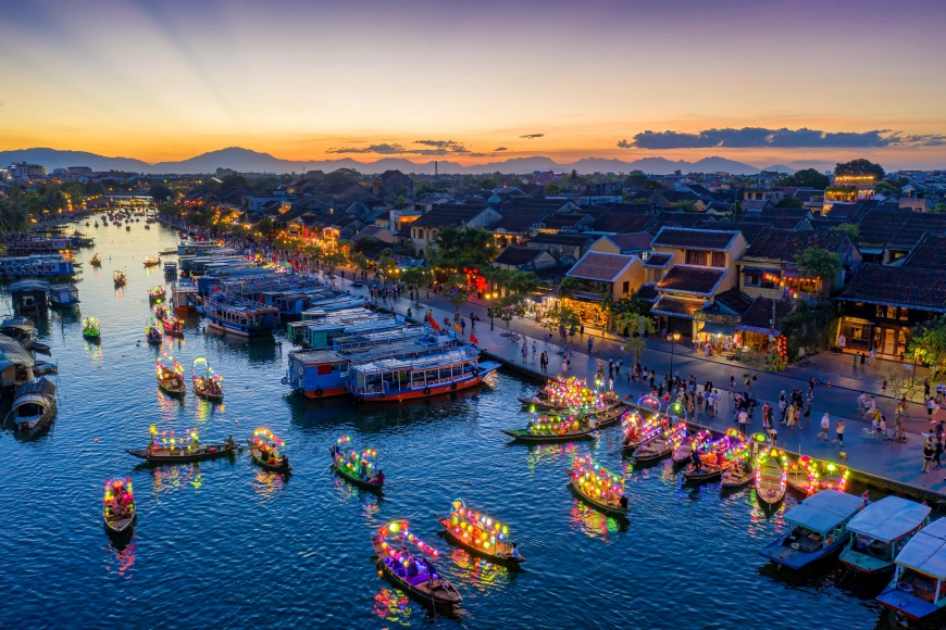 Colorful lantern boats glowing on the Thu Bon River in Hoi An at sunset.