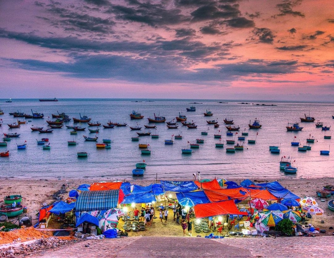 Traditional round basket boats and fishing vessels at Mui Ne Fishing Village during sunset.