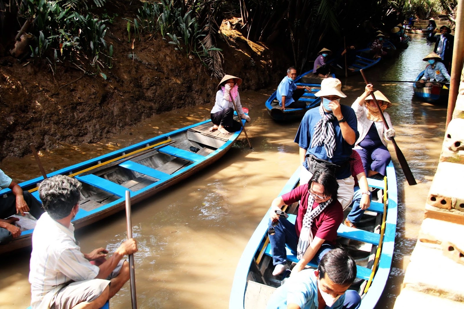 Small wooden boat ride through narrow coconut canals in Con Thoi Son, Mekong Delta
