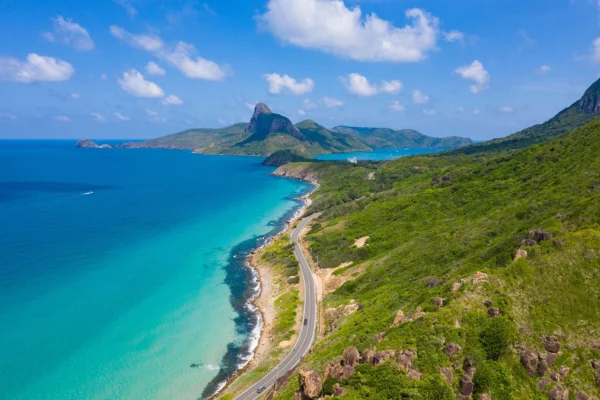 Scenic coastal road winding along turquoise sea and green mountains in Con Dao.
