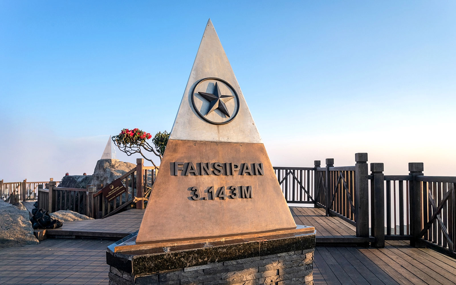 Fansipan summit marker at 3,143 meters above sea level with visitors celebrating at the top.