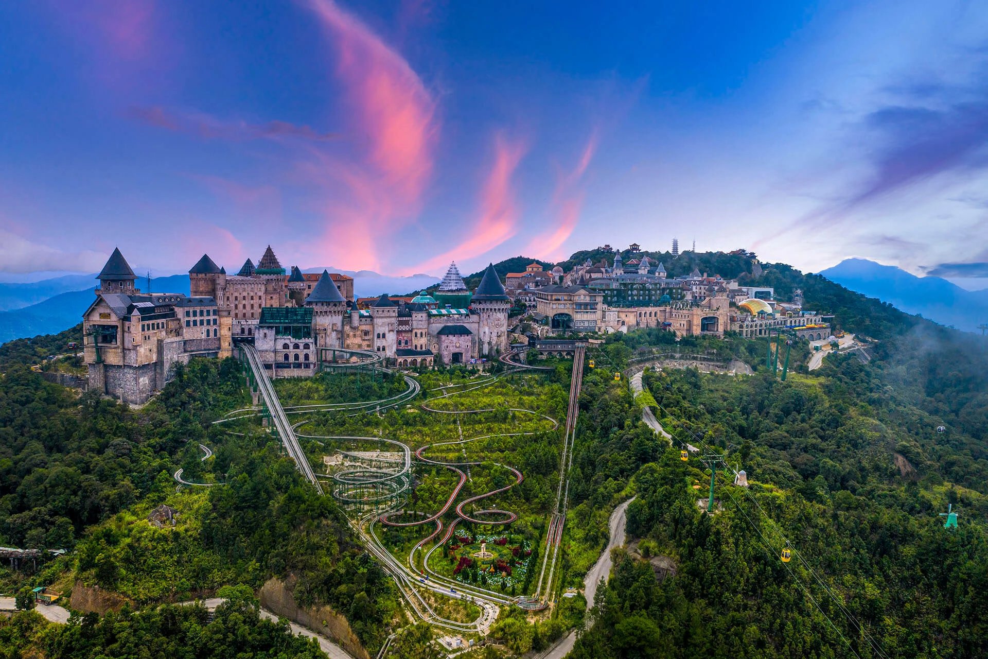 Panoramic view of the European-style French Village Ba Na Hills at sunset with castle architecture and mountain scenery.