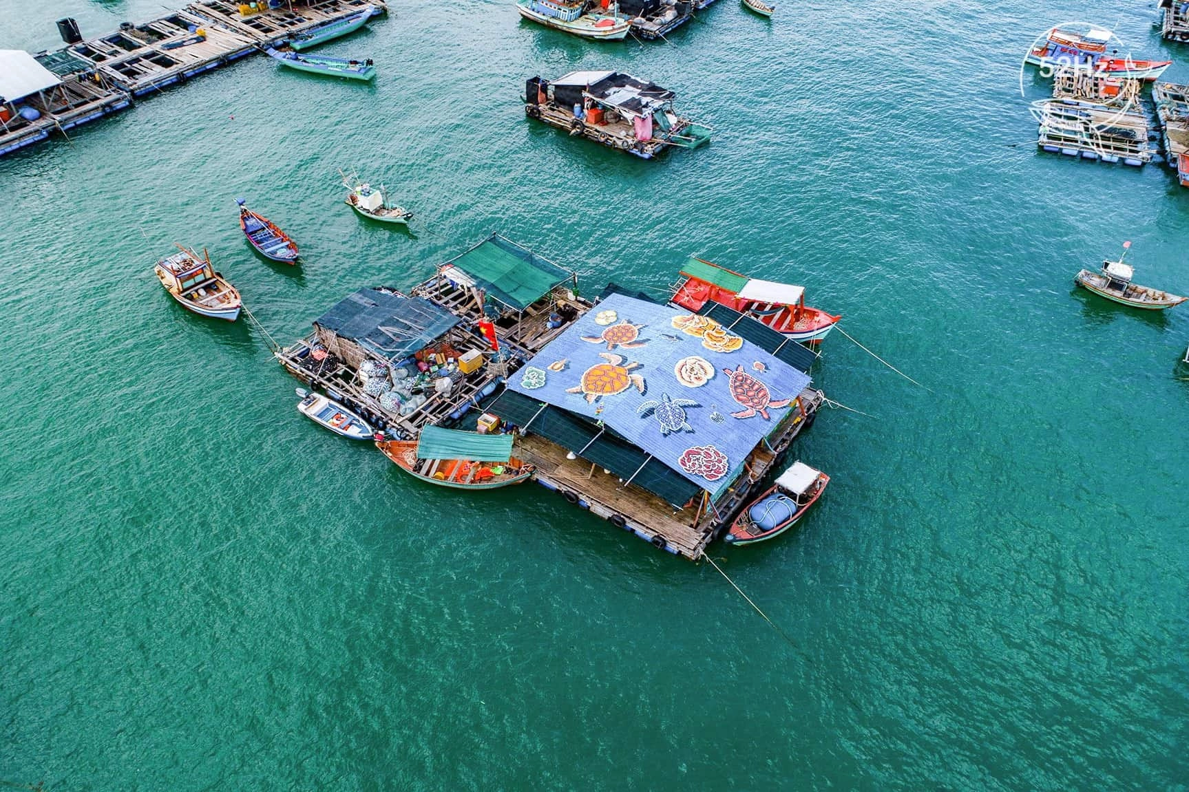 Colorful fishing boats anchored near Hon Son fishing village with houses along the shoreline