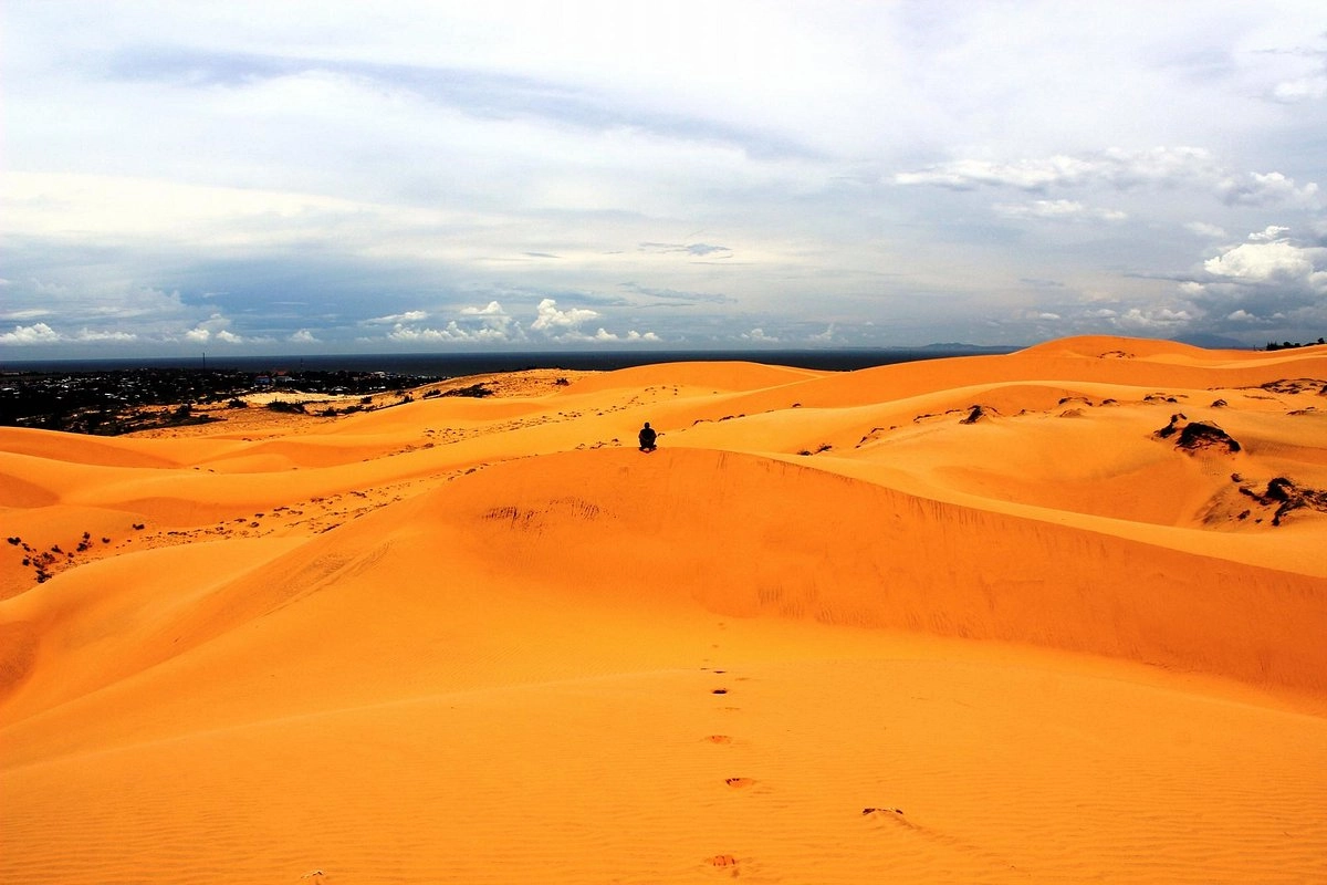 Golden-orange landscape of Red Sand Dunes Mui Ne with rolling hills and footprints.