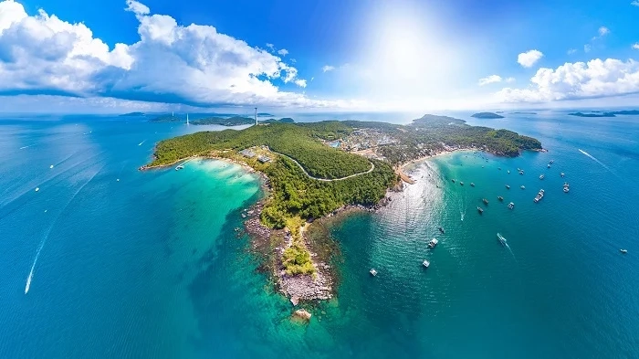Aerial panoramic view of turquoise sea and lush green coastline on Phu Quoc with fishing boats and tropical landscape.