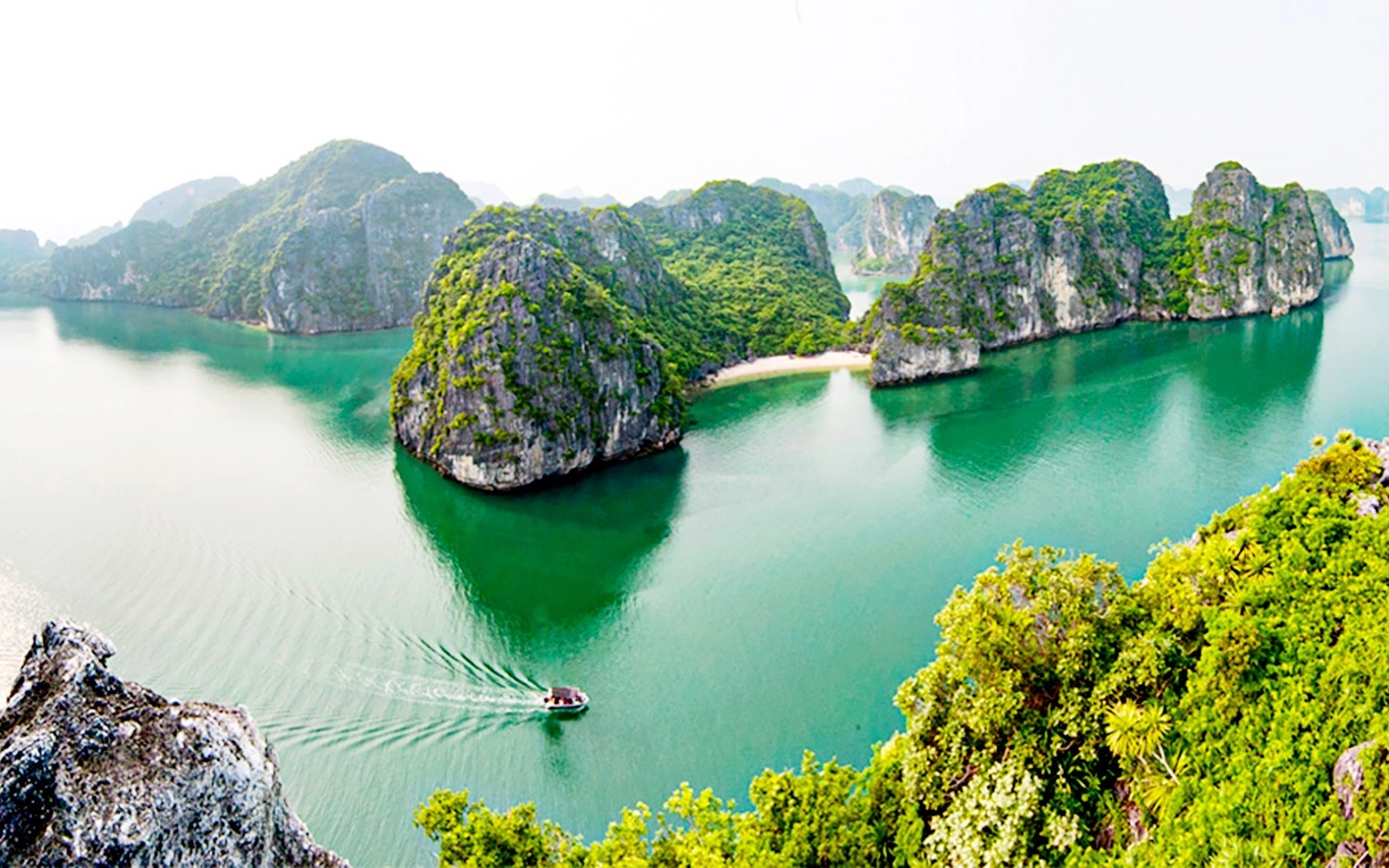 Scenic coastal landscape of Quang Ninh with green hills, islands, and clear blue sea under a bright sky