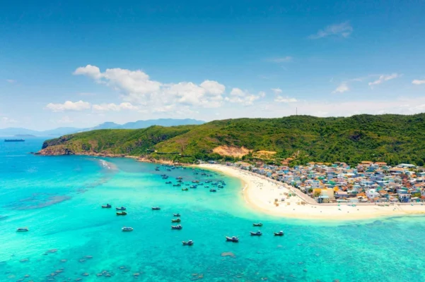 Panoramic view of Quy Nhon coastline with fishing boats, turquoise sea, and a seaside village