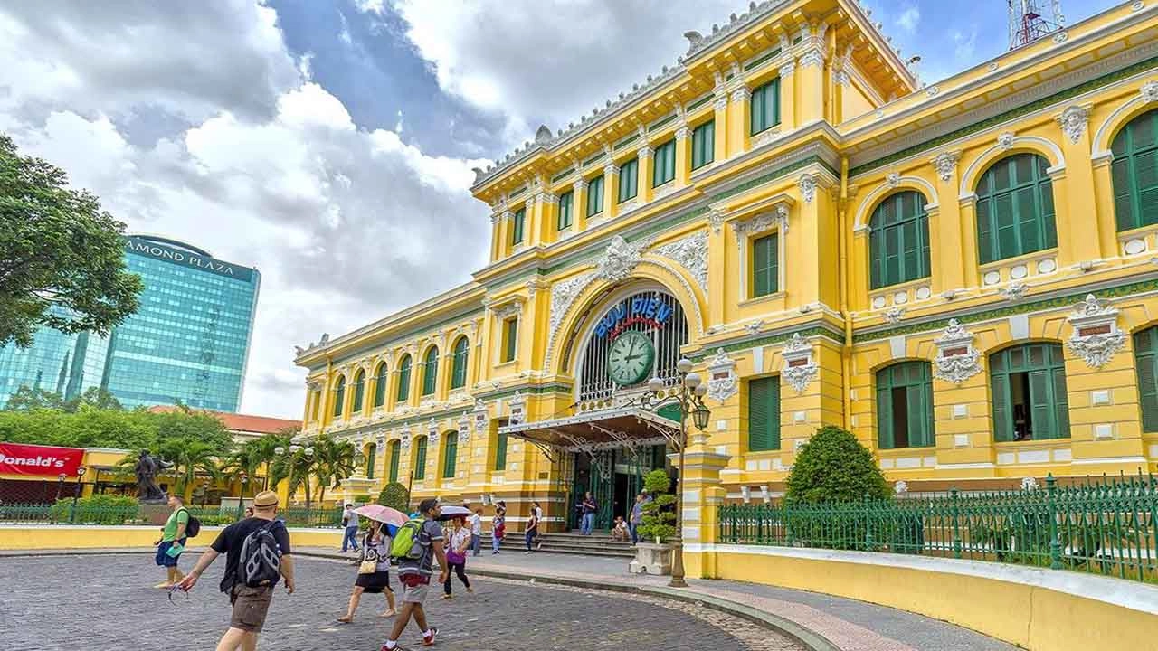 Interior of Saigon Central Post Office with arched ceilings, vintage design, and bustling visitors.