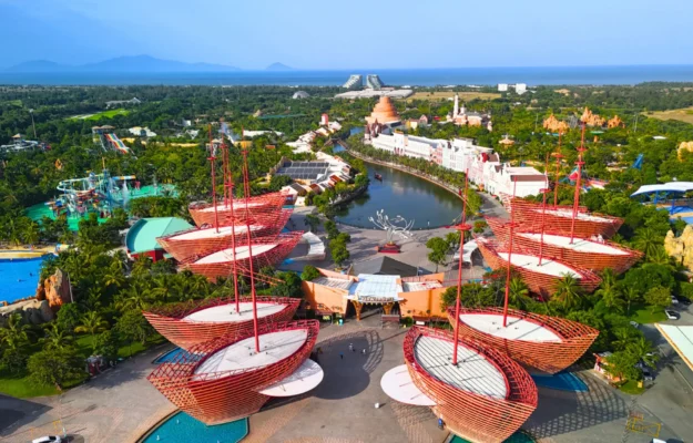Aerial view of VinWonders Phu Quoc featuring colorful boat-shaped architecture, water park attractions, green landscapes, and ocean scenery with StarTour