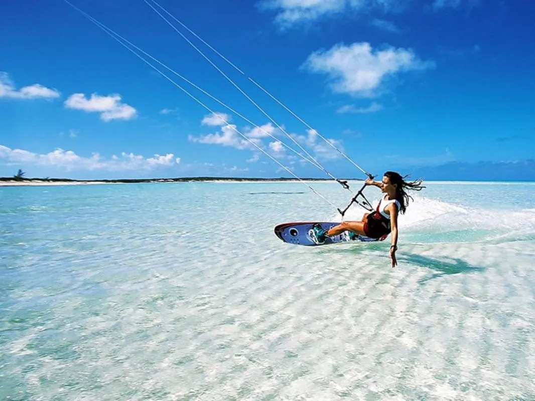 Woman kitesurfing over crystal clear turquoise water on a sunny tropical beach