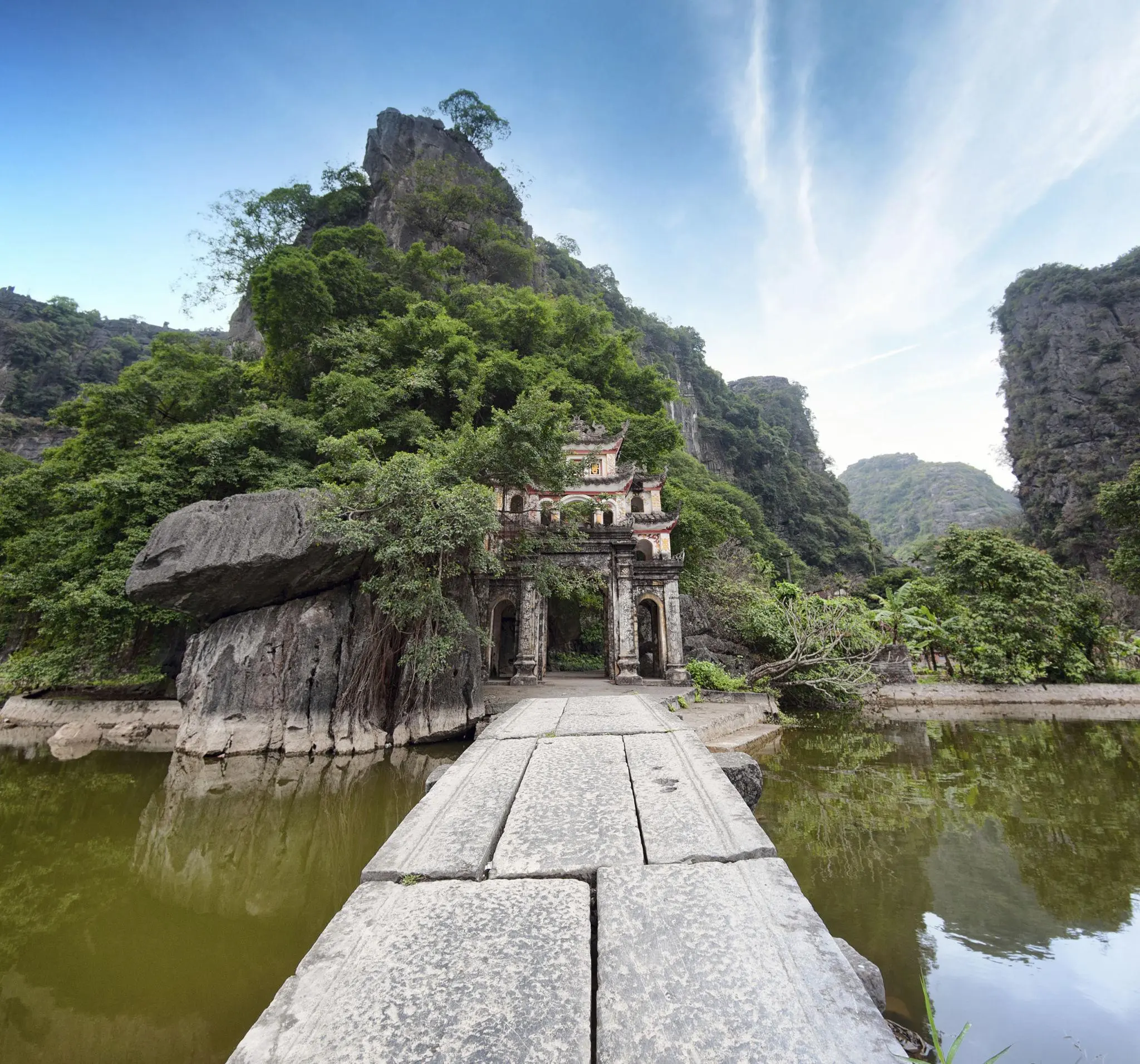Ancient stone bridge leading to the iconic gate of Bich Dong Pagoda, a cultural highlight of Ninh Binh travel