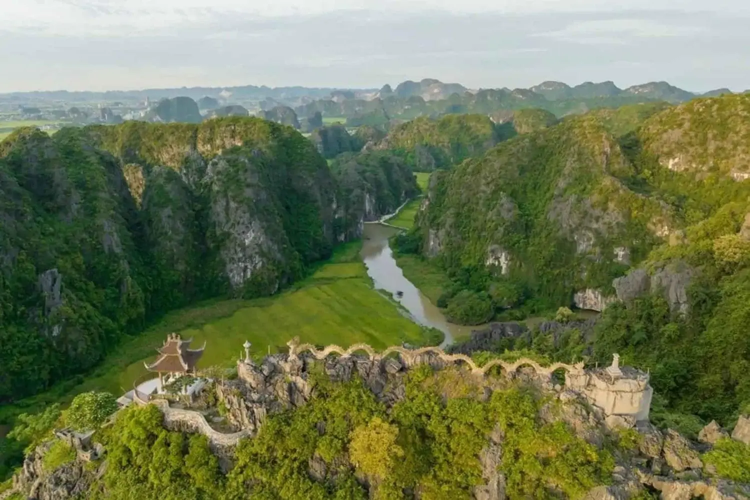 Panoramic view from Mua Cave peak showing the iconic dragon statue and lush valleys during a Ninh Binh travel trip