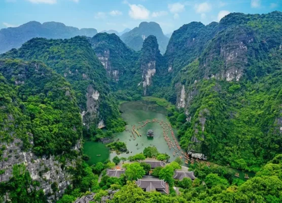 Ninh Binh travel experience featuring a scenic boat tour winding through the majestic karst mountains of Trang An