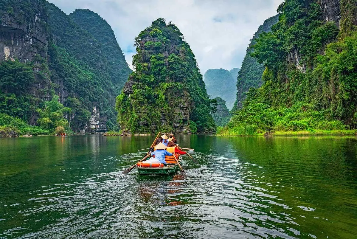 Tourists enjoying a traditional boat ride in Trang An valley during their Ninh Binh travel trip