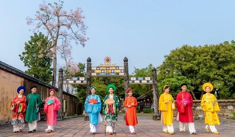Tourists wearing colorful traditional Nhat Binh royal garments in front of an ceremonial gate at Hue Imperial Citadel with startour.