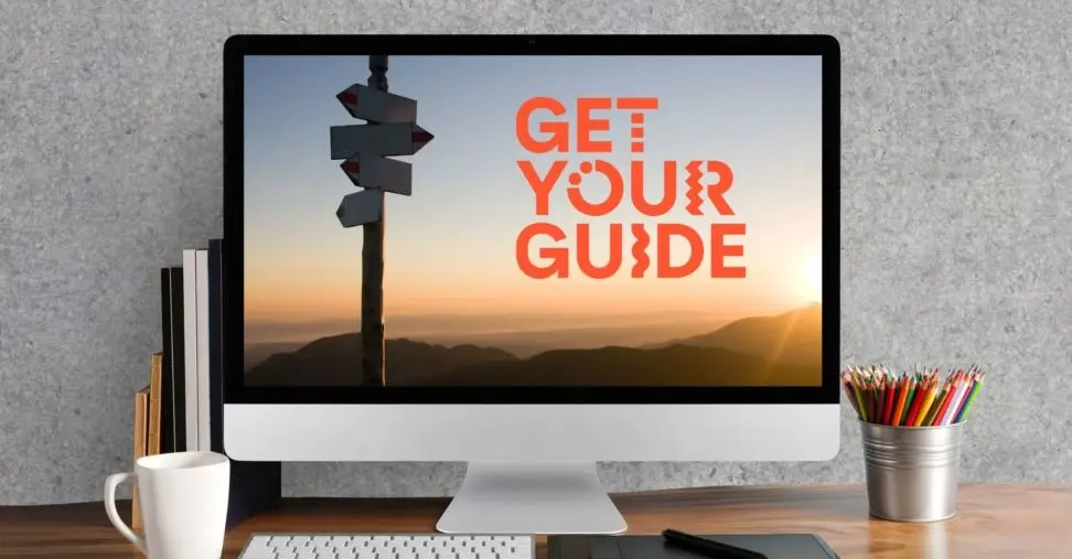 Desktop display showing GetYourGuide logo set against a mountain sunrise background when comparing Klook vs Viator vs GetYourGuide by startour.