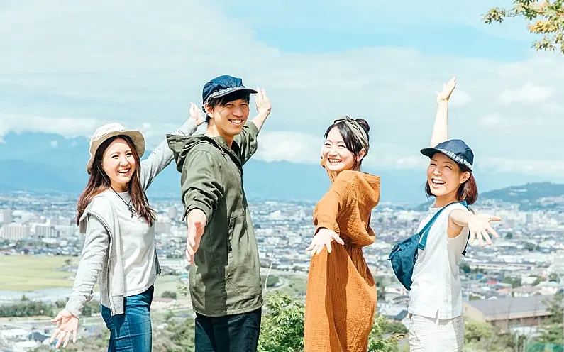 Four cheerful friends on a mountain viewpoint, enjoying a trip planned through what is OTA tour booking by starTOUR.