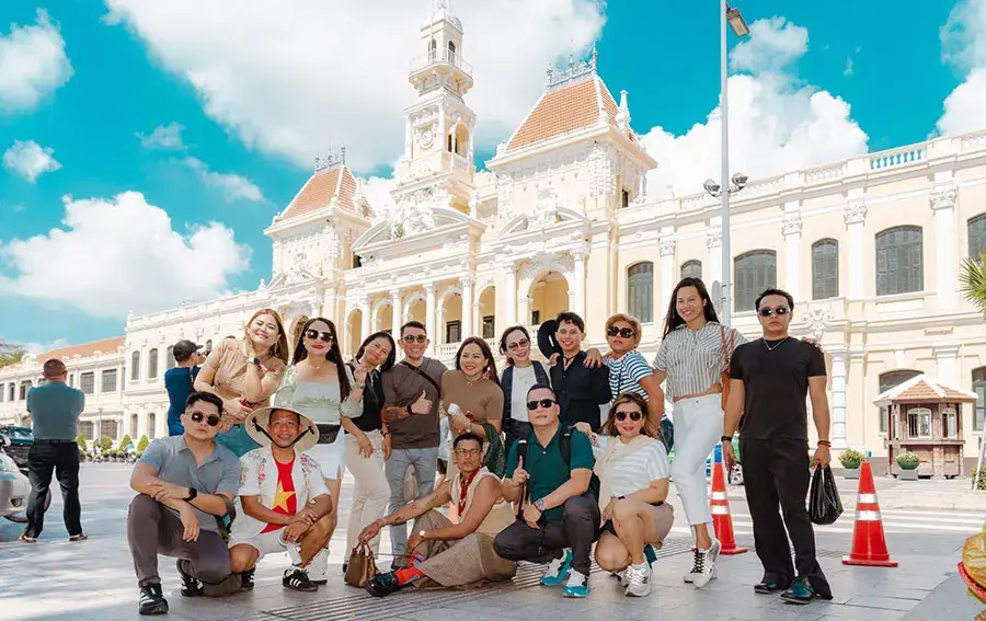 A group of tourists in front of Ho Chi Minh City Hall, experiencing what is OTA tour booking with starTOUR.